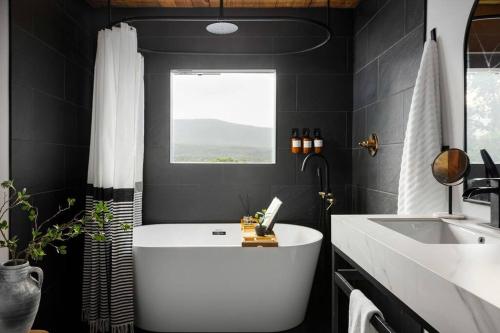 een badkamer met een wit bad en een wastafel bij Riverside Rose Cabin: Luxe*LogCabin*MtnView*Sleeps12*Secluded*Shenandoah in Rileyville