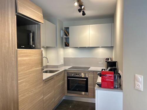 une petite cuisine avec une cuisinière et un micro-ondes dans l'établissement Appartement de Standing au Centre des Gets, Proche Pistes, 2 Ch, Terrasse, Parking, WiFi - FR-1-623-6, aux Gets