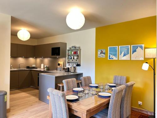 une salle à manger avec une table et des chaises et une cuisine dans l'établissement Luxueux Appartement au Centre des Gets avec Jardin, Proche Pistes, 3 Chambres, Wi-Fi, Parking - FR-1-623-338, aux Gets