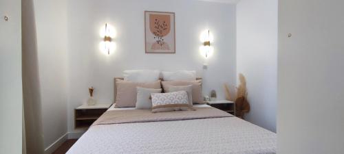 1 dormitorio con 1 cama grande con sábanas y almohadas blancas en Chez Adriana Appartement Cosy avec Jardin, proche plage en Grimaud