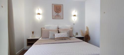 une chambre avec un grand lit avec des draps et des oreillers blancs dans l'établissement Chez Adriana Appartement Cosy avec Jardin, proche plage, à Grimaud