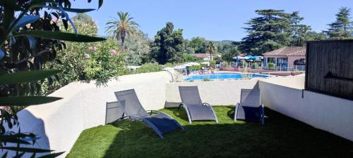 - un groupe de chaises assises sur l'herbe près d'une piscine dans l'établissement Chez Adriana Appartement Cosy avec Jardin, proche plage, à Grimaud
