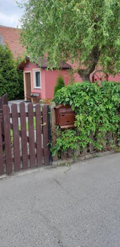 a wooden fence in front of a pink house at Apartament u Janiny in Jeżów Sudecki