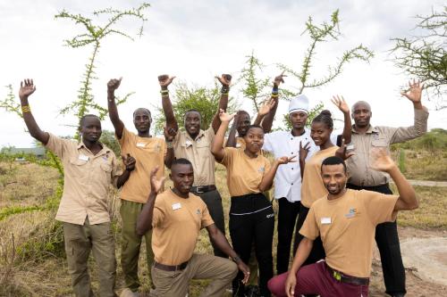 a group of men posing for a picture with their hands in the air at Africa Safari Serengeti Ikoma Camping in Serengeti