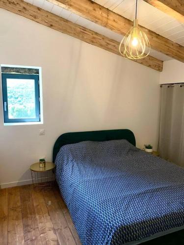 une chambre avec un lit bleu et une fenêtre dans l'établissement Caseddu au coeur du village, à Monacia-dʼAullène
