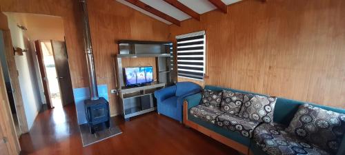 un salon avec un canapé bleu et une télévision dans l'établissement Los aromos, à Lago Ranco