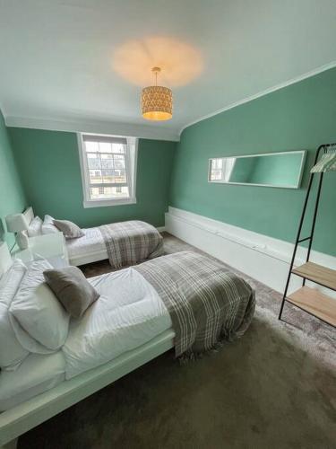 two beds in a room with blue walls at The Great Pulteney Penthouse, Bath City Centre in Bath