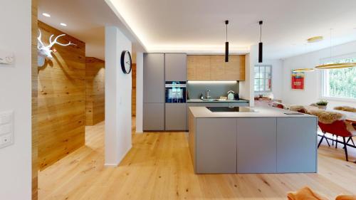 a kitchen and living room with white walls and wood floors at Cresta Ellie in St. Moritz