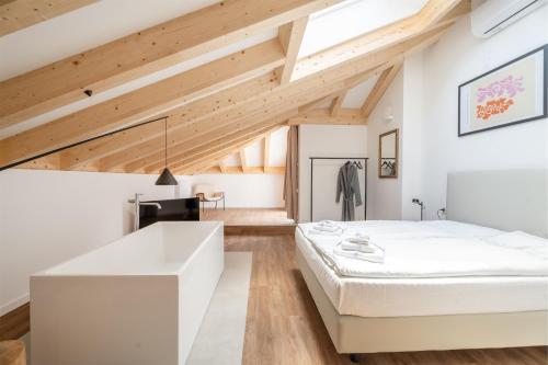 Schlafzimmer mit einem großen weißen Bett und Holzdecken in der Unterkunft Casa Al Sole in Tenno