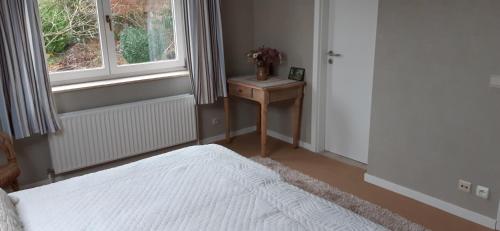 een slaapkamer met een bed, een tafel en een raam bij Les 3 Fontaines in Verviers