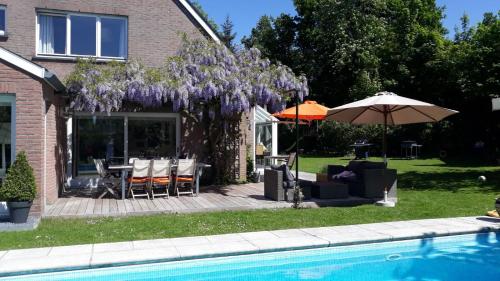 a house with a picnic table and an umbrella next to a pool at Les 3 Fontaines in Verviers