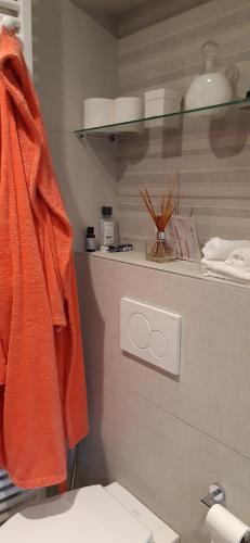 een oranje handdoek op een plank boven een toilet bij Les 3 Fontaines in Verviers