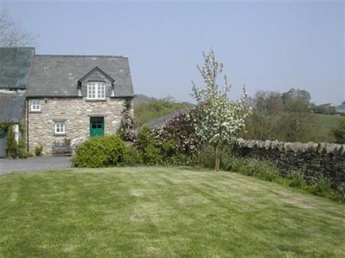 a stone house with a green door and a yard at Alltybrain Farm Cottages and Farmhouse B&B in Brecon