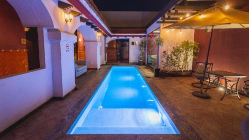 a swimming pool in a room with a table and an umbrella at Casa Eva Hotel Boutique & Spa in Cholula