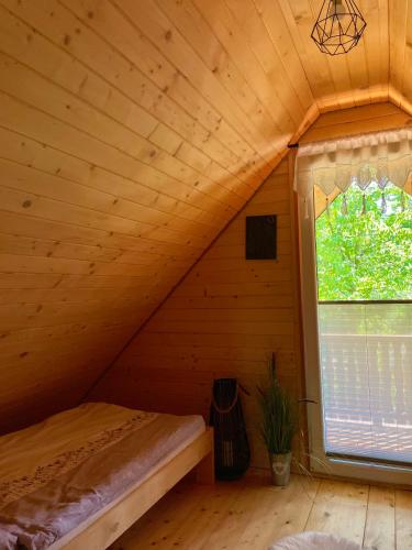 a bedroom with a bed in a wooden room with a window at Domek Nida in Polańczyk