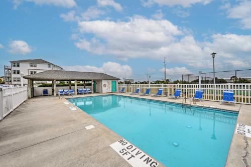 a swimming pool with blue chairs and a building at Ocean Front Emerald Isle Vacation Rental Property in Emerald Isle