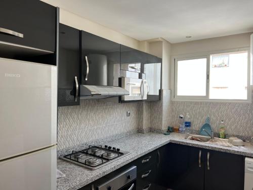 a kitchen with black cabinets and a stove top oven at Appartement jad in Casablanca