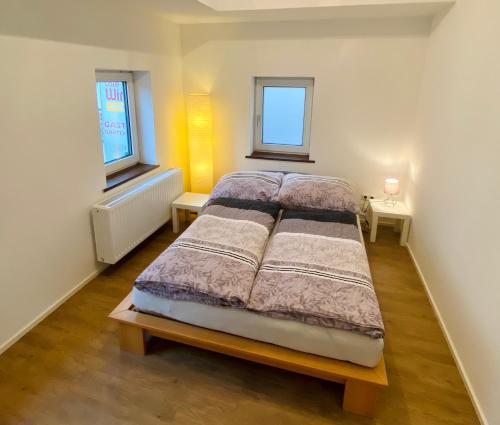 a bed in a room with two windows at Ferien-Wohnung für 1-4 Pers in Seenähe in Timelkam