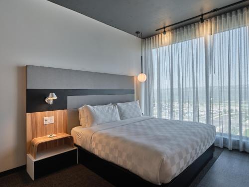 a bedroom with a large bed and a large window at Alt Hotel Calgary University District in Calgary