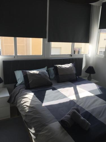 a bedroom with a large bed with two windows at ViNALUX in Vinaròs