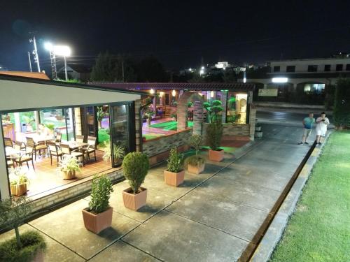 a restaurant with potted plants on a patio at night at Drini Hotel in Durrës