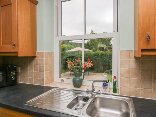 a kitchen with a sink and a window with flowers at Netherbeck Cottage in Carnforth