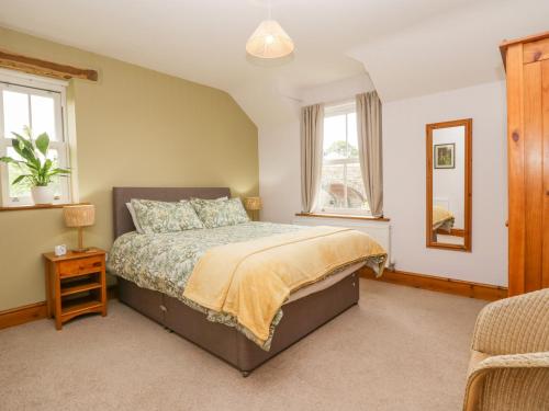 a bedroom with a bed and two windows at Netherbeck Cottage in Carnforth