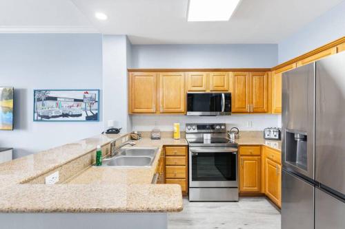a kitchen with wooden cabinets and a stainless steel refrigerator at Spectacular view Blue Heron Beach Resort Near Disney in Orlando