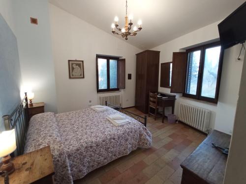 a bedroom with a bed and a desk and windows at All'Ombra di San Damiano in Assisi
