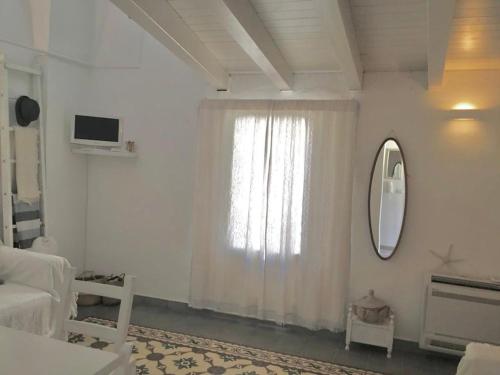 um quarto branco com uma janela e um espelho em Casa Annina em Gallipoli