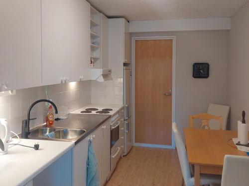 a kitchen with a sink and a stove and a table at Lakeside Villa Lehtiniemi in Pirkkala