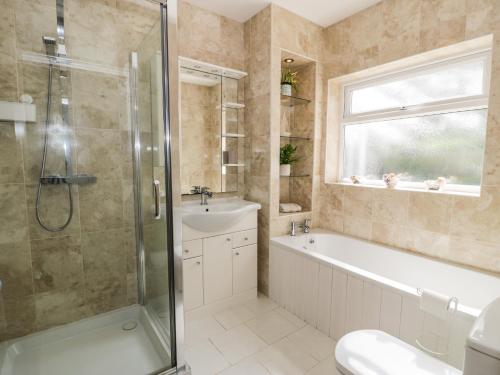 a bathroom with a shower and a tub and a sink at 24 Dolithel in Tywyn