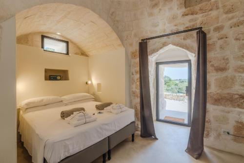 a bedroom with a large bed and a window at Trulli Meridiem con Piscina in Ostuni