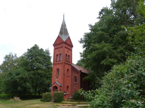 une église en briques rouges avec une cloche au-dessus dans l'établissement Jagdhaus Franz, 