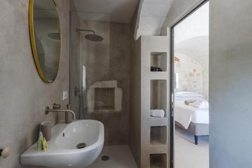 a bathroom with a sink and a mirror and a bed at Trulli Meridiem con Piscina in Ostuni