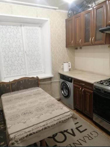 eine Küche mit einem Tisch, einem Herd und einem Fenster in der Unterkunft Квартира рядом с Вокзалом in Dnipro