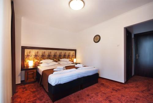 a hotel room with two beds and a clock on the wall at Hotel Moldavia in Slănic-Moldova