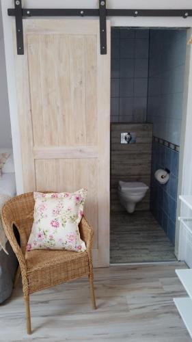 a bathroom with a wicker chair and a toilet at Folwark Leszczynówka in Srebrna Góra