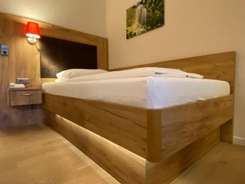 a large wooden bed in a room with a lamp at Hotel Sonnenhügel in Bad Bevensen