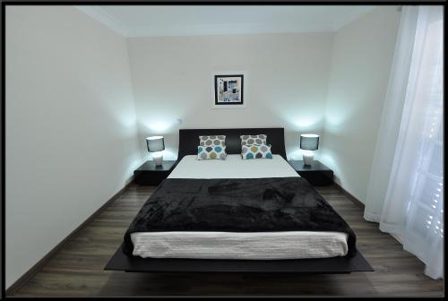 a bedroom with a large bed and two lamps at Vila Beatriz in Alcantarilha