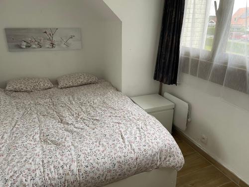a white bedroom with a bed and a window at Chouette appartement 5 personnes in De Haan