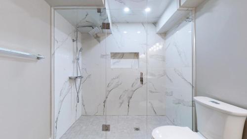 a white bathroom with a shower and a toilet at Stunning 2BR Lower Level Unit in Vaughan