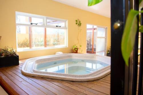 a jacuzzi tub in a room with two windows at Hotel San Carlos in San Antonio de Areco