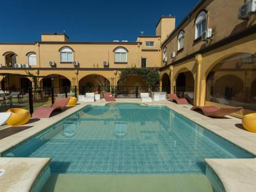 a large swimming pool with chairs and a building at Hotel San Carlos in San Antonio de Areco