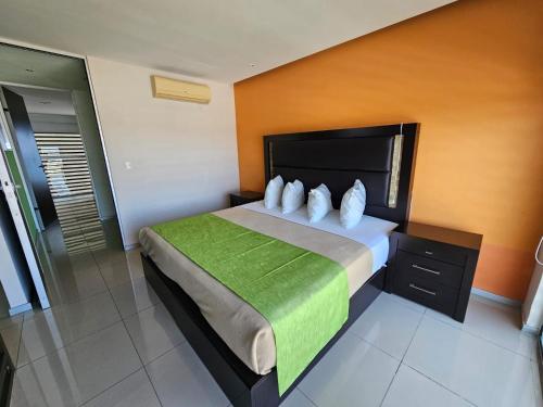 a bedroom with a large bed with a green blanket at Hotel Torres Eugenia in Coatzacoalcos