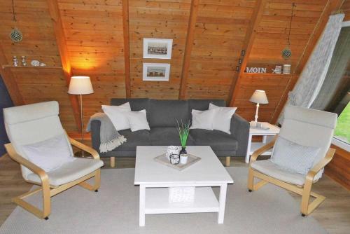 een woonkamer met een bank, 2 stoelen en een tafel bij Zeltdachhaus mit W_LAN in Strandna in Damp
