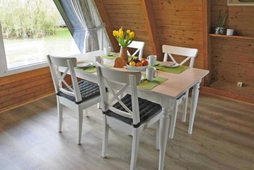 een witte eettafel met stoelen en bloemen erop bij Zeltdachhaus mit W_LAN in Strandna in Damp