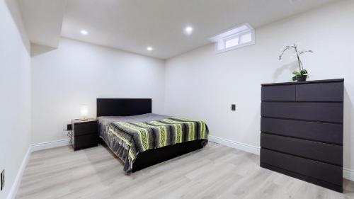 a white bedroom with a bed and a dresser at Stunning 2BR Lower Level Unit in Vaughan
