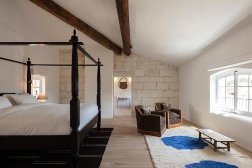 a bedroom with a poster bed and a chair at Maison Salix in Vallabrègues