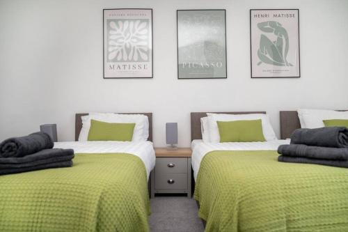 a bedroom with two beds with green sheets and posters at Spacious Home In The Heart of West Yorkshire in Brighouse